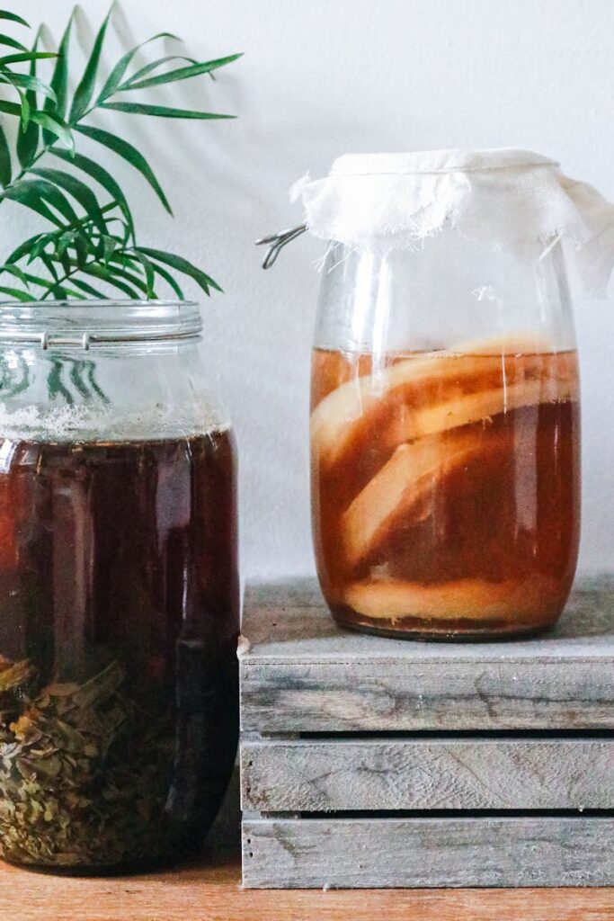 Jars with kombucha and dark herbal beverage -kombucha needs to be refrigerated 